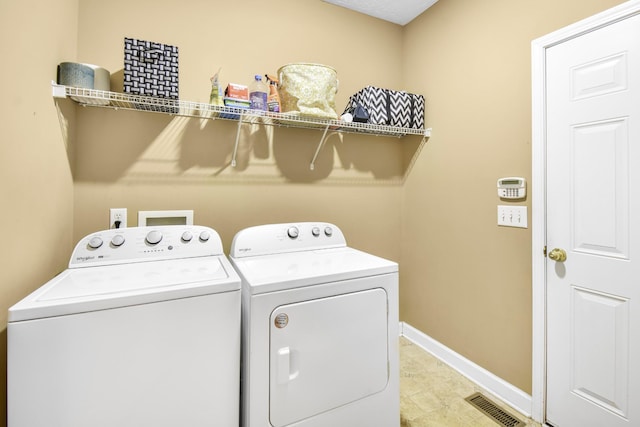 washroom featuring washing machine and clothes dryer, baseboards, laundry area, and visible vents