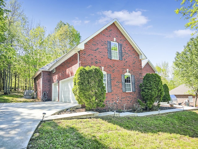 view of side of property with brick siding, driveway, a garage, and a lawn