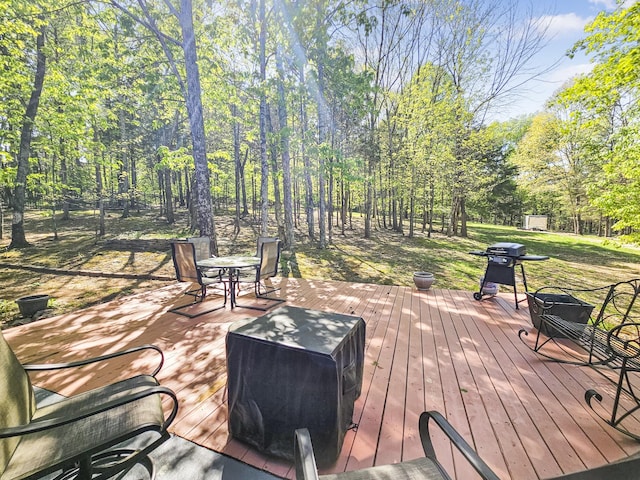 wooden deck with outdoor dining space, a lawn, and a grill