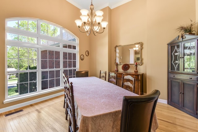 dining room featuring light wood-style flooring, visible vents, a notable chandelier, and plenty of natural light