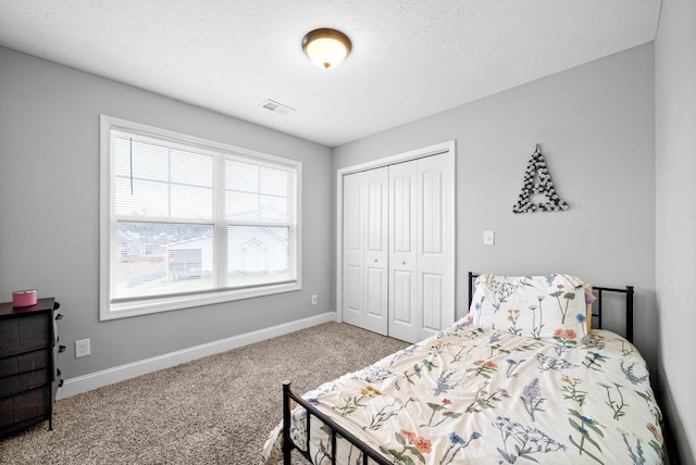 bedroom featuring carpet, visible vents, a closet, baseboards, and a textured ceiling