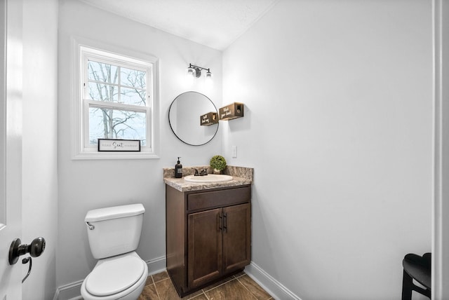 bathroom with vaulted ceiling, vanity, toilet, and baseboards