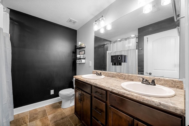 bathroom with visible vents, a sink, double vanity, and toilet