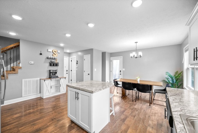 kitchen with white cabinets, dark wood-style floors, visible vents, an inviting chandelier, and recessed lighting