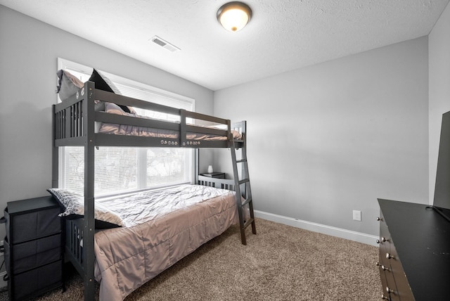 bedroom featuring a textured ceiling, visible vents, carpet flooring, and baseboards