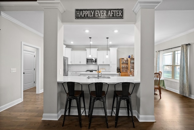 1885 Shield Dr, Clarksville, TN 37043 - kitchen featuring stainless steel appliances, a peninsula, dark wood-style floors, and ornate columns