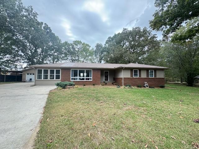 ranch-style home with an attached garage, a front lawn, driveway, and brick siding