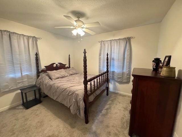 carpeted bedroom with a textured ceiling, a ceiling fan, and baseboards
