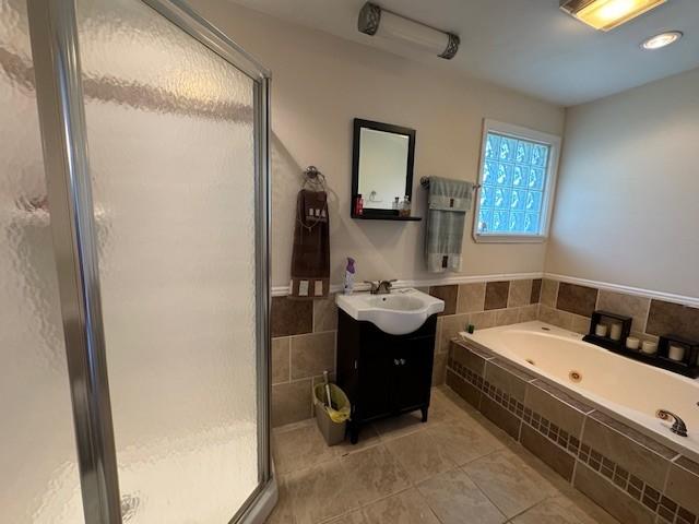 full bath featuring a stall shower, tile walls, a whirlpool tub, tile patterned flooring, and vanity