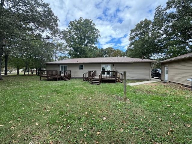 back of property with a lawn and a deck