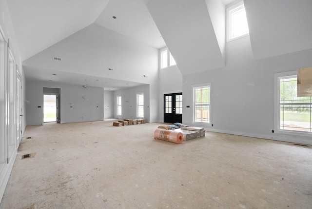 unfurnished living room featuring visible vents, a towering ceiling, and a healthy amount of sunlight