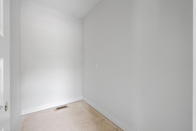 empty room featuring concrete floors, visible vents, and baseboards