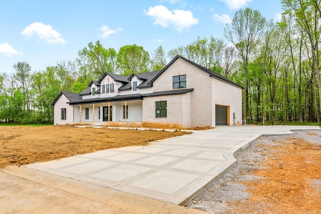 view of front of home featuring brick siding, covered porch, and concrete driveway