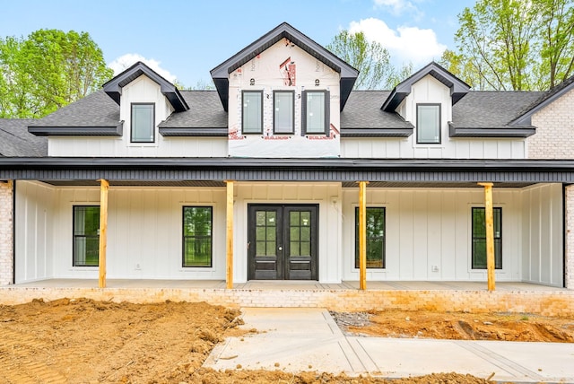 doorway to property featuring board and batten siding, french doors, and roof with shingles