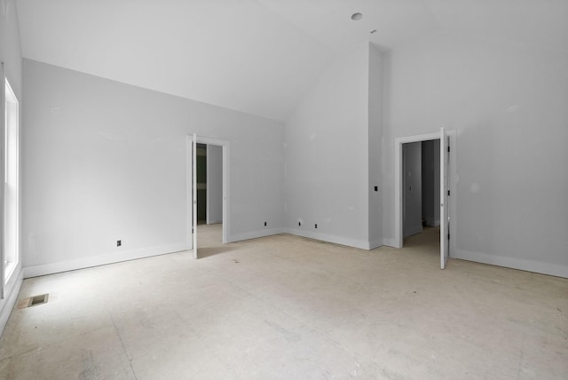 spare room with concrete floors, baseboards, visible vents, and high vaulted ceiling
