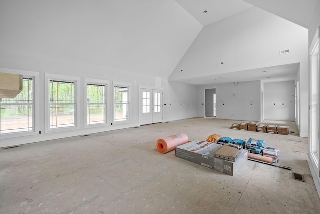 unfurnished living room featuring high vaulted ceiling, french doors, and visible vents