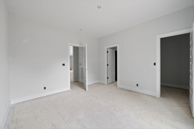 unfurnished bedroom featuring a walk in closet and baseboards