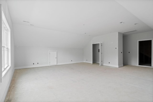 additional living space featuring baseboards, lofted ceiling, and a wealth of natural light