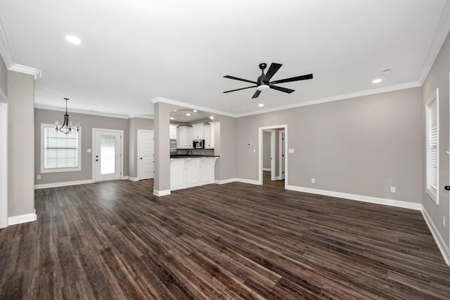 unfurnished living room featuring ceiling fan with notable chandelier, baseboards, and dark wood-type flooring