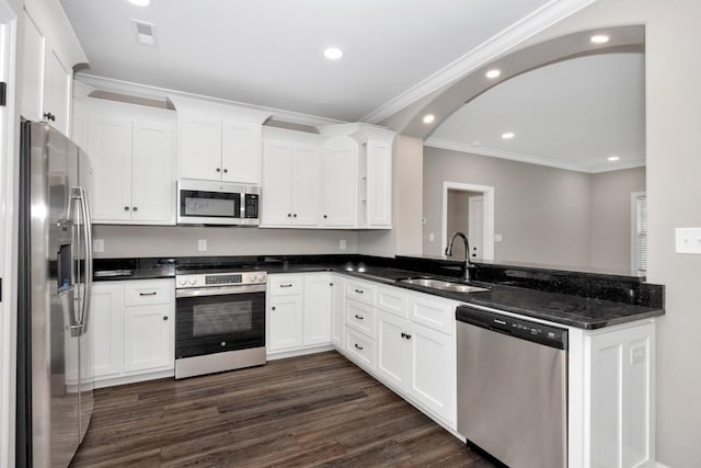 kitchen with white cabinets, stainless steel appliances, ornamental molding, a sink, and a peninsula
