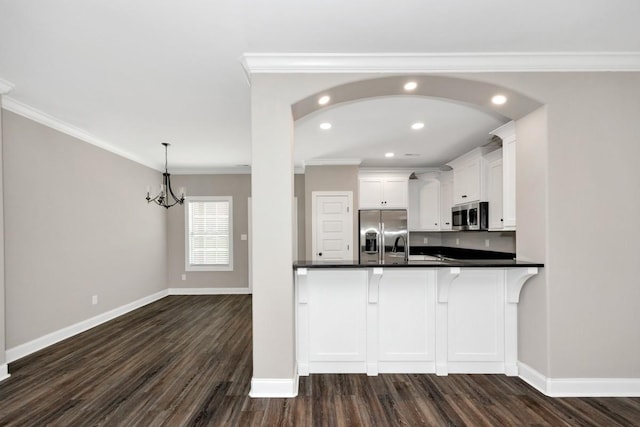 kitchen with dark countertops, appliances with stainless steel finishes, crown molding, and dark wood-style floors