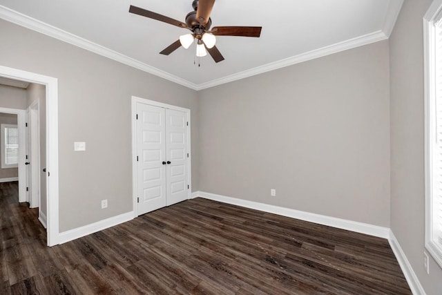 unfurnished bedroom featuring a ceiling fan, crown molding, a closet, baseboards, and dark wood-style flooring