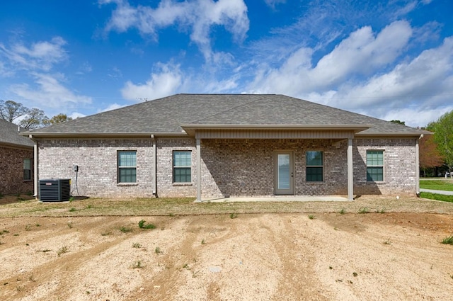 rear view of house featuring cooling unit, roof with shingles, a patio, and brick siding