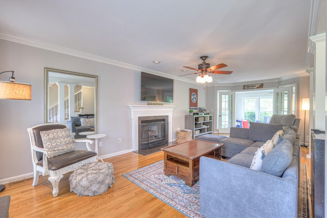 living room with baseboards, a ceiling fan, wood finished floors, and crown molding