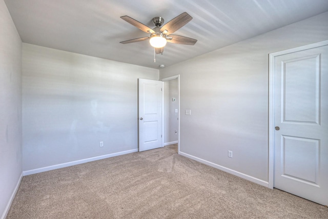 carpeted empty room with baseboards and a ceiling fan