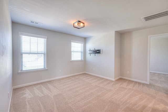 carpeted empty room featuring baseboards and visible vents
