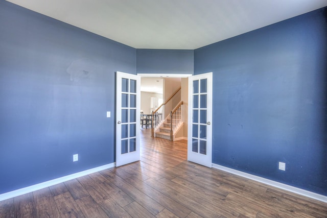spare room featuring baseboards, french doors, wood finished floors, and stairs