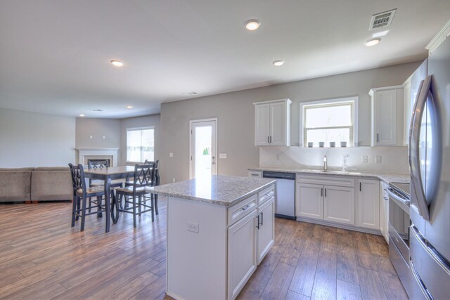 kitchen featuring a sink, open floor plan, visible vents, hardwood / wood-style floors, and appliances with stainless steel finishes