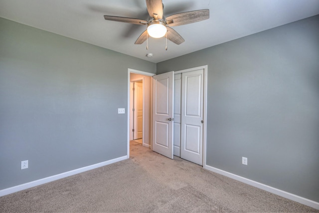 unfurnished bedroom featuring light carpet, baseboards, a closet, and ceiling fan