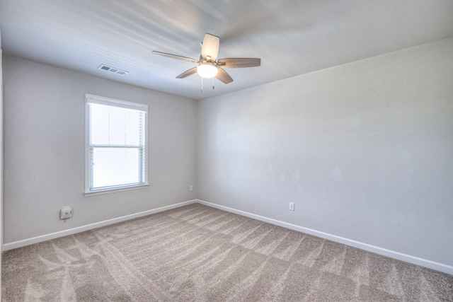carpeted spare room with baseboards, a ceiling fan, and visible vents