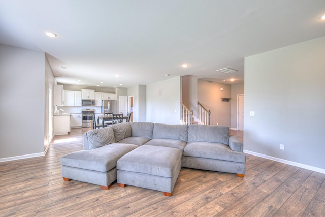 living room with light wood finished floors, visible vents, and recessed lighting
