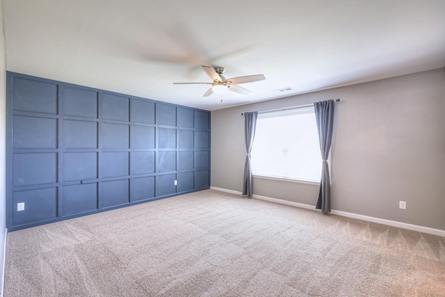 spare room with visible vents, carpet floors, a decorative wall, baseboards, and ceiling fan