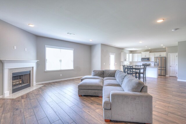living area featuring recessed lighting, a high end fireplace, visible vents, and a wealth of natural light
