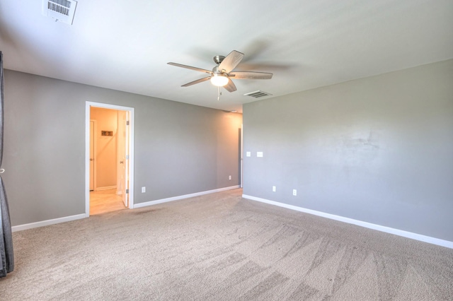 carpeted empty room with baseboards, a ceiling fan, and visible vents