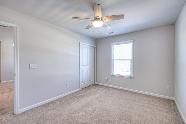 spare room with baseboards, visible vents, a ceiling fan, and light colored carpet