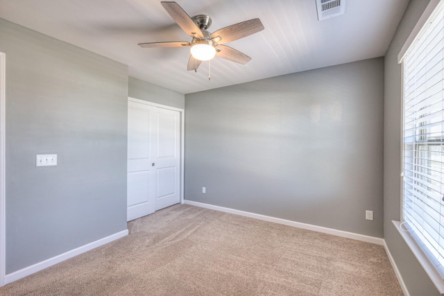 empty room with baseboards, a ceiling fan, visible vents, and carpet floors