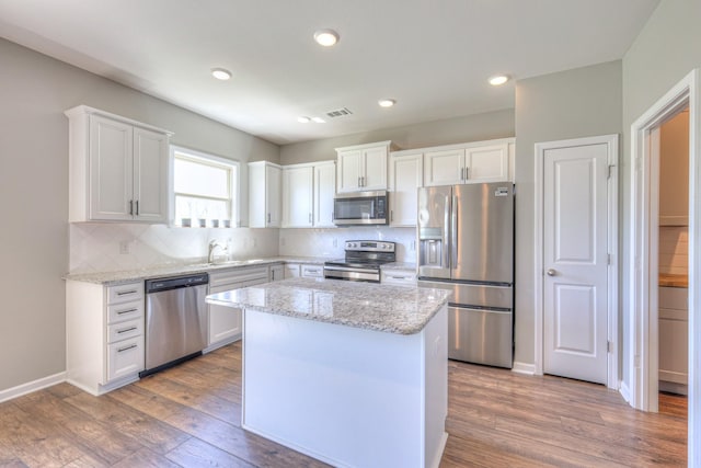 kitchen featuring white cabinets, stainless steel appliances, backsplash, visible vents, and a sink