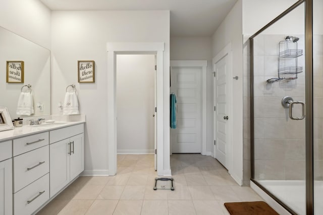 bathroom featuring tile patterned flooring, baseboards, vanity, and a stall shower