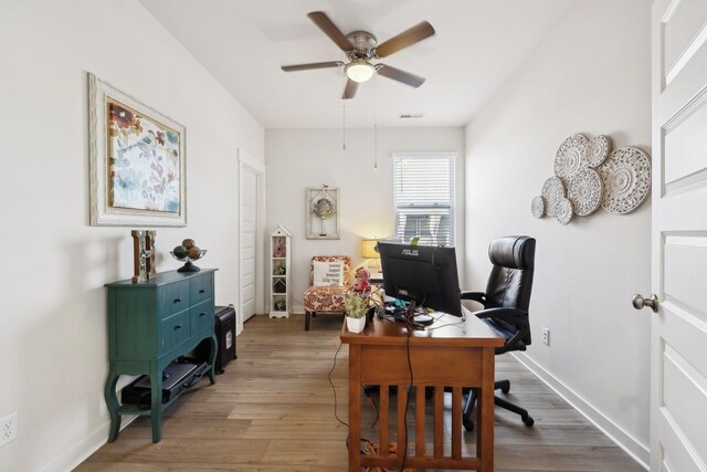 home office featuring wood finished floors, visible vents, a ceiling fan, and baseboards