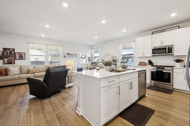 kitchen with light countertops, open floor plan, stainless steel appliances, and a sink