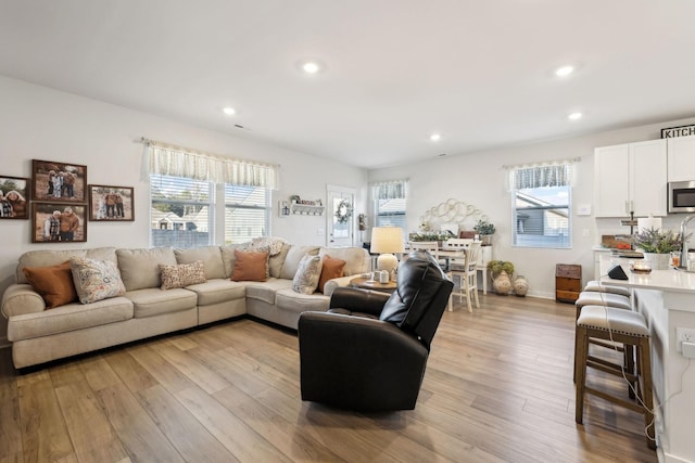 living room with recessed lighting, light wood-type flooring, and baseboards