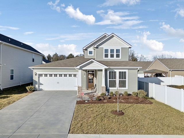 view of front of property featuring a front lawn, fence, driveway, and a garage