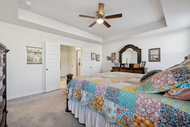 bedroom featuring a tray ceiling, carpet flooring, baseboards, and a ceiling fan