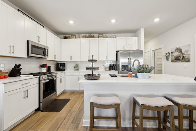 kitchen featuring a kitchen breakfast bar, tasteful backsplash, stainless steel appliances, and light countertops