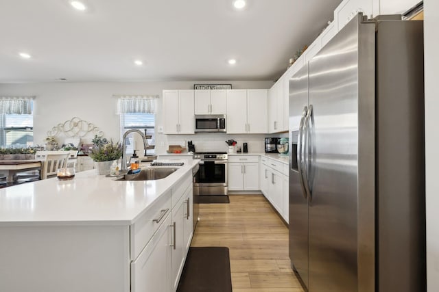 kitchen with recessed lighting, light countertops, a sink, appliances with stainless steel finishes, and white cabinetry