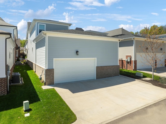 view of side of home with central air condition unit, concrete driveway, a yard, a garage, and brick siding